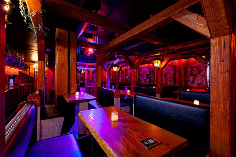 Barinteriør med sitteplasser omgitt av neonlys
