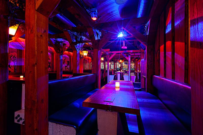 Barinteriør med sitteplasser omgitt av neonlys