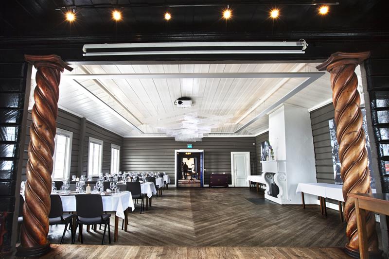 Restaurantinteriør. Peis, dekket bord med hvite duker og stoler.