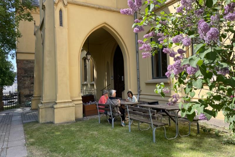 Tre personer sitter utenfor Bispegården