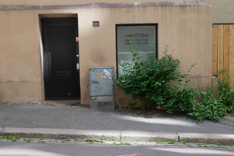 Inngangen til Van Etten. En svart dør i en lysebrun vegg.