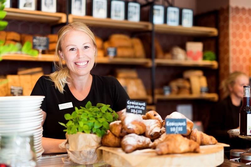 en kvinnelig arbeider smiler på et bakeri
