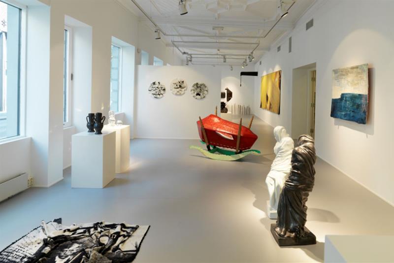 Galleriinteriør med skulpturer og malerier på veggene.