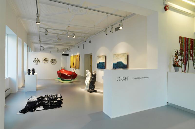 Galleriinteriør med skulpturer og malerier på veggene.