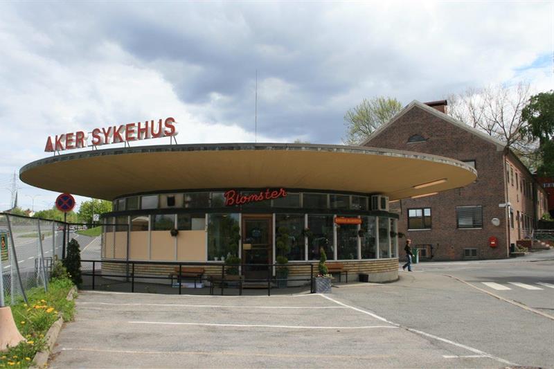 Rund bygning med blomsterbutikk på innsiden. Skilt på toppen med teksten "Aker sykehus"