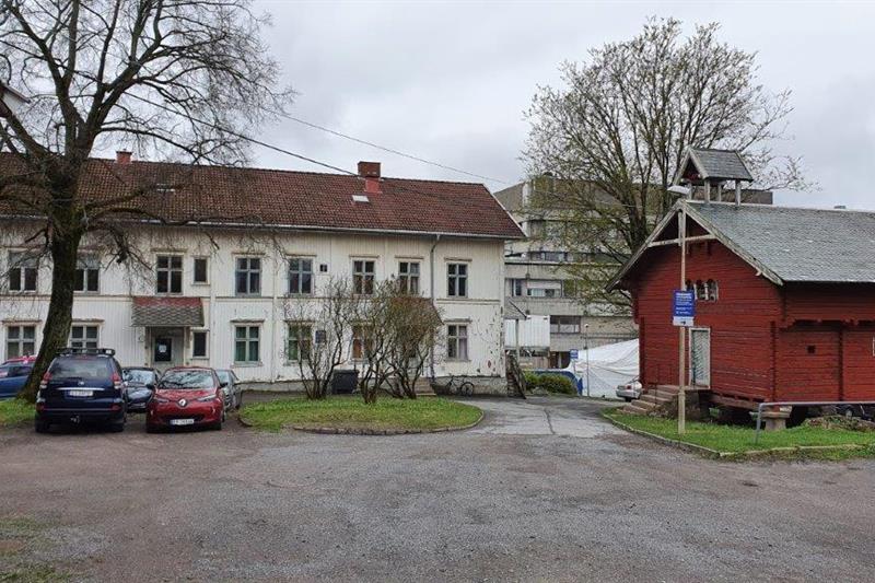 Rødt, tradisjonelt lagerhus. Hvitt hus, parkerte biler.