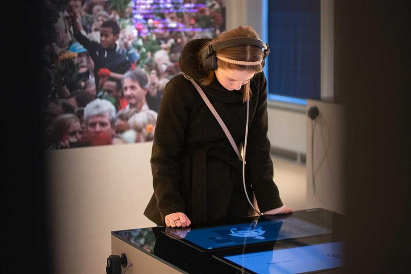 Jente med hodetelefoner ser på en skjerm i utstillingen
