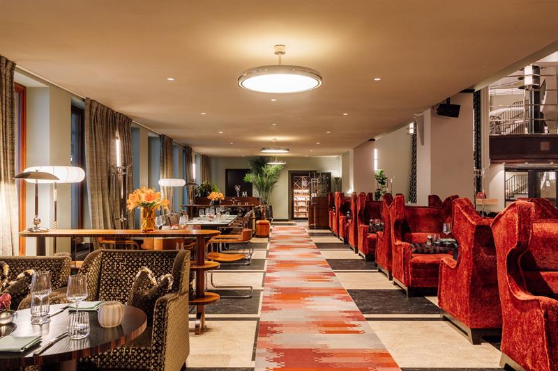 Elegant hotellsalong med komfortable lenestoler, langbord, tepper i varme farger og en innbydende atmosfære.