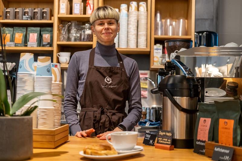 Smilende barista bak disken