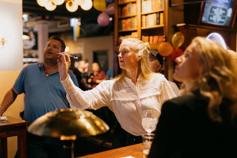 Kvinne i ferd med å kaste en pil mens noen andre ser på