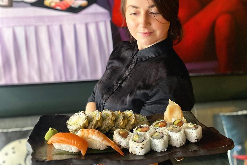 Servitrisen bærer en sushitallerken.