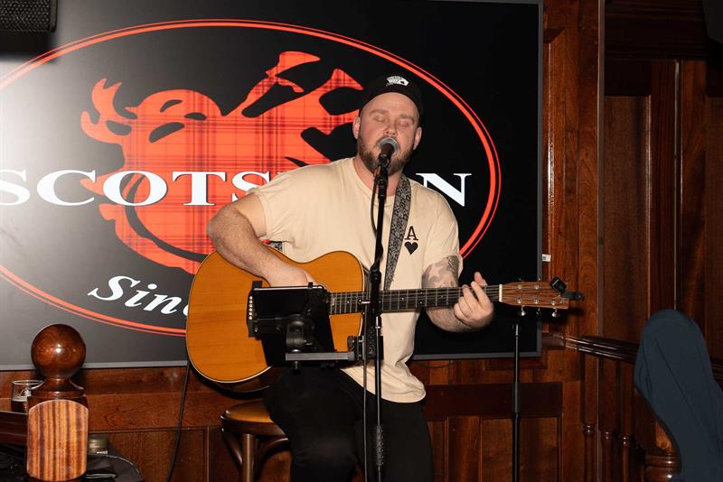 Mann opptrer med gitar på scenen