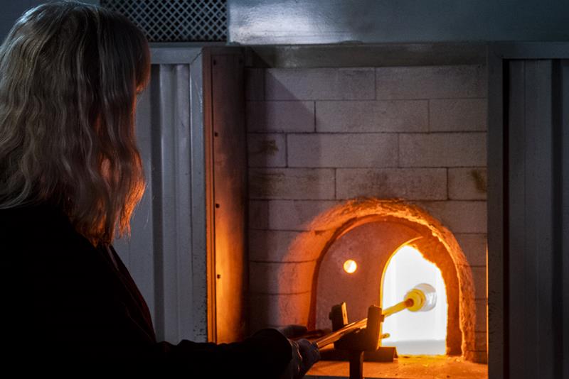 Kvinne som varmer opp et glass i en glassovn