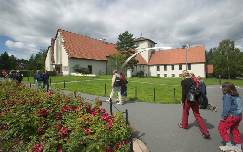 Utsiden av museet, med en plen og rosenbusker foran.