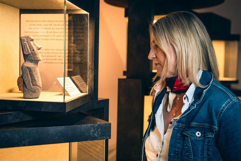 Kvinne som ser på en miniskulptur fra Påskeøya