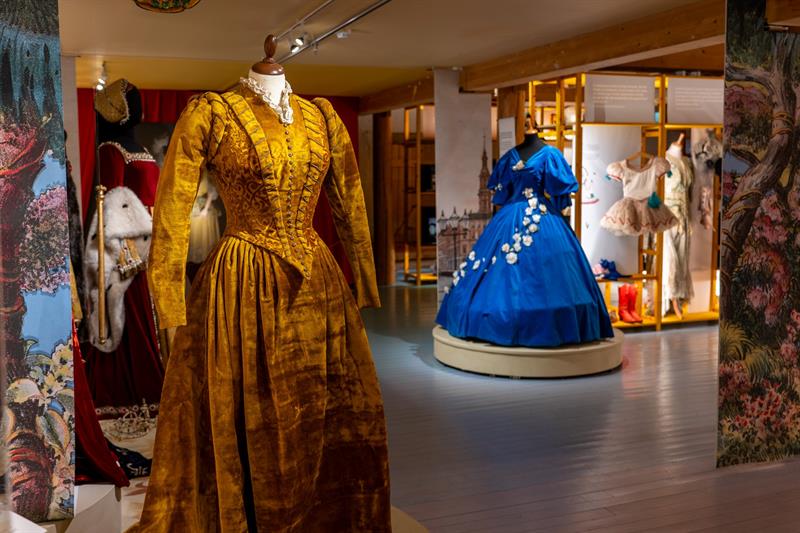 Museumsutstilling med historiske kostymer og scenedrakter presentert i åpne gallerirom med tekst og illustrasjoner.