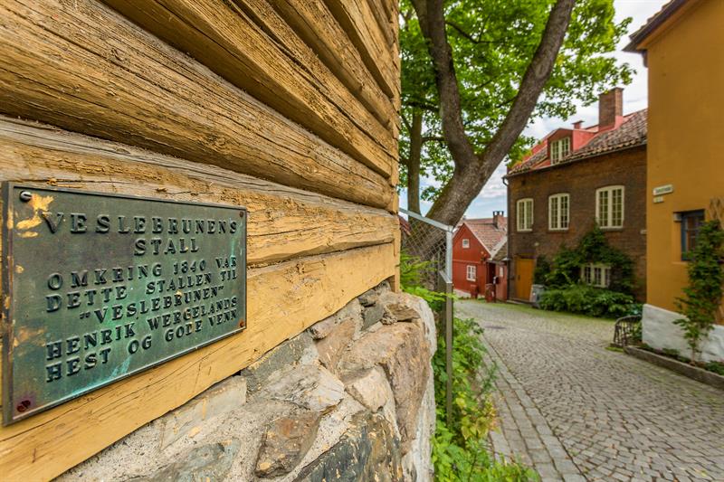 Plakett på et gammelt, gult trehus.