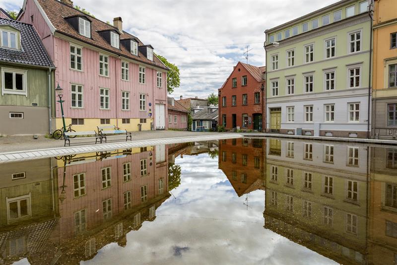 Gamle trehus rundt en plass med et basseng.