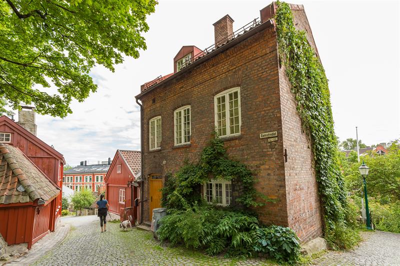 Mursteinshus øverst i telthusbakken med klatreplante langs veggen.