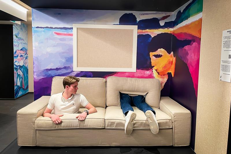 En beige sofa med en gutt som stikker hodet ut av et hull, mens et par ben stikker ut av et annet hull ved siden av ham.