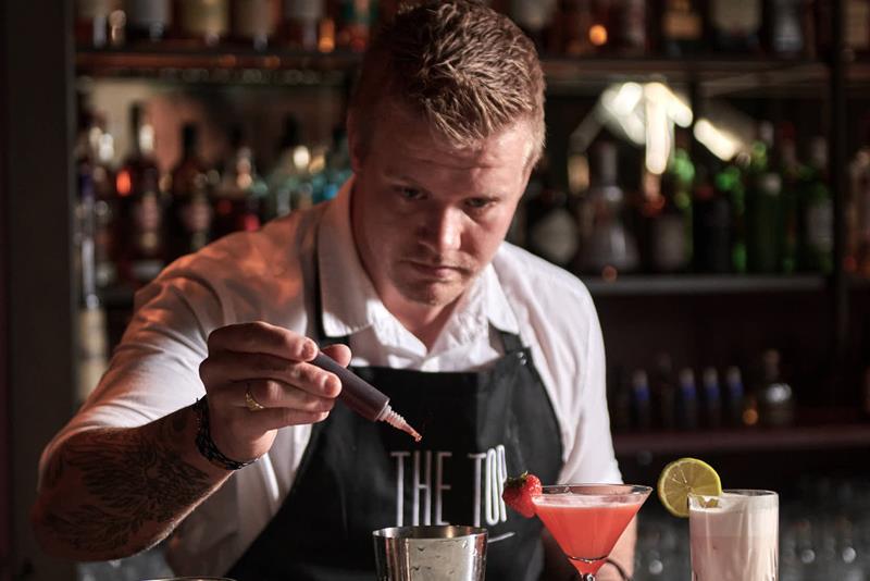 En bartender på The Top drypper ingredienser i en shaker.