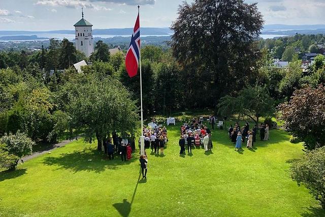 Folk som står på plenen, samlet rundt en flaggstang.