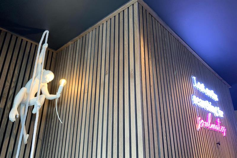 Nærbilde av en kunstinstallasjon foran en trevegg.