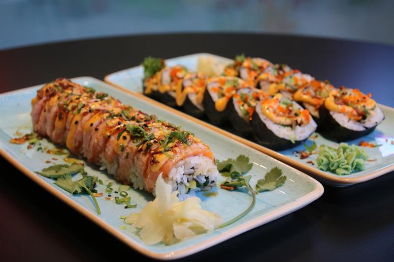 Detaljbilde av to lyseblå tallerkener med nigiri og maki-ruller på, samt ingefær og wasabi.