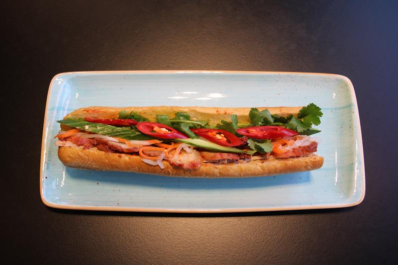 Nærbilde av en bánh mì-baguette på en blå tallerken.