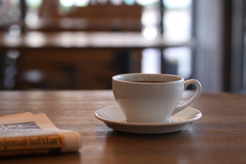 Nærbilde av en kaffekopp og en avis.
