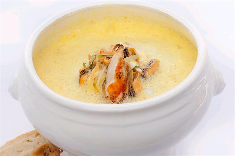 Detaljbilde av en skål fylt med suppe, med to brødskiver ved siden av.