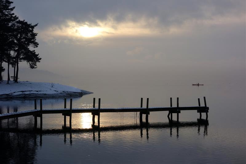 Overskyet himmel på vinteren med en liten brygge ut mot havet.