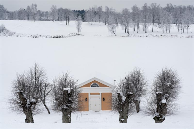 Et lite gult hus i et snødekt landskap.