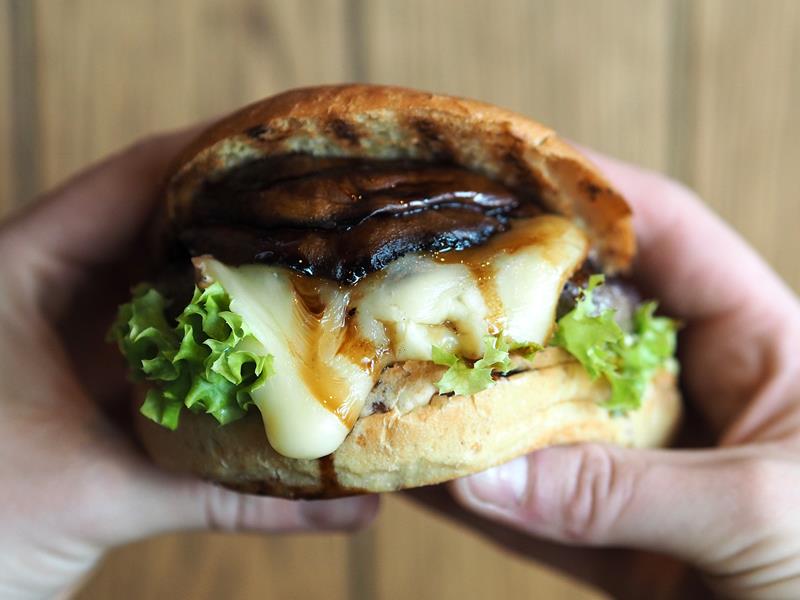 Detaljbilde av en burger som holdes med begge hender.