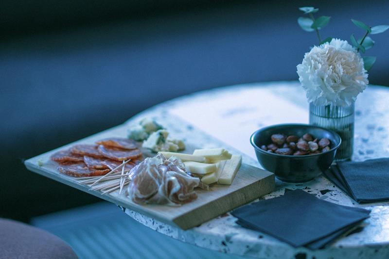 Lite bord med spekemat, ost og snacks servert på et fat i en bar.
