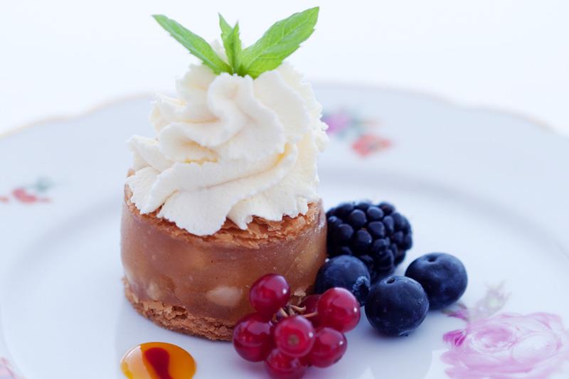 Detaljbilde av en dessert på en hvit tallerken med blomster på.