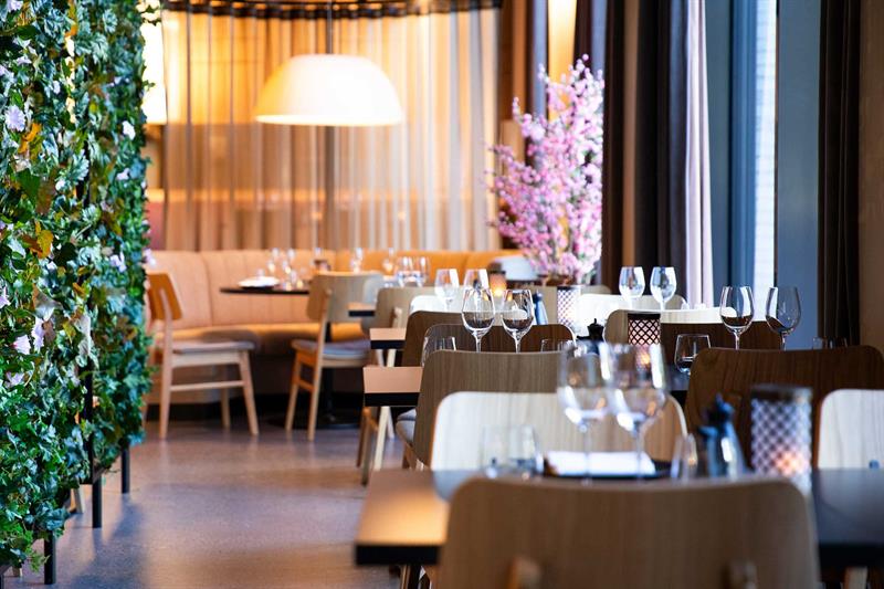 Restaurantinteriør med bord dekket til måltid og stoler