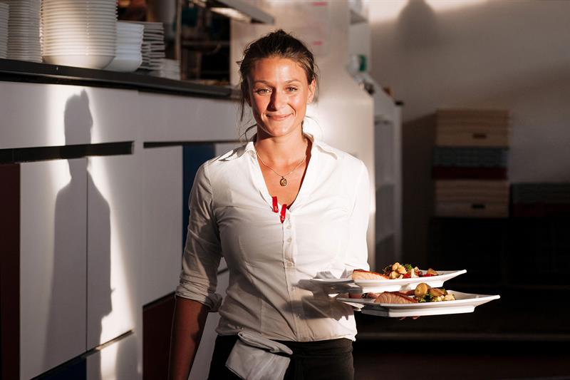 servitør med tallerkener i hånden