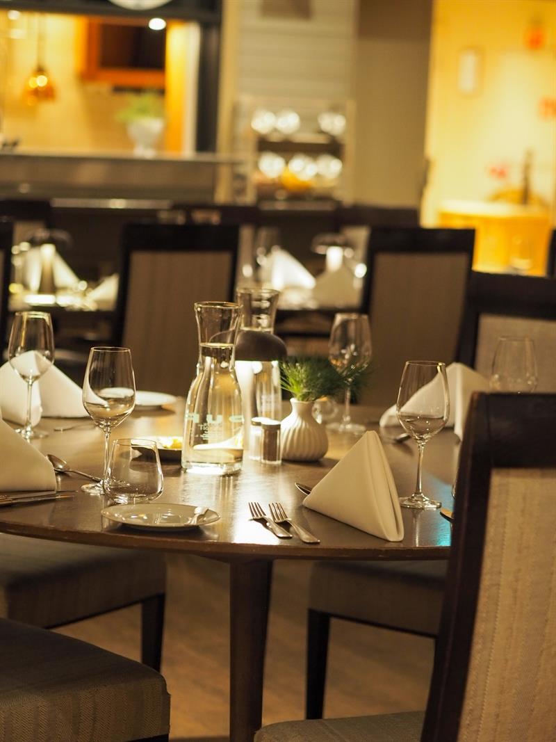En stemningsfull restaurant med dekket bord, dempet belysning og en varm atmosfære.