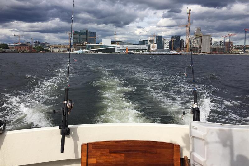 fiskestang festet til en båt, utsikt over fjorden og Oslos skyline