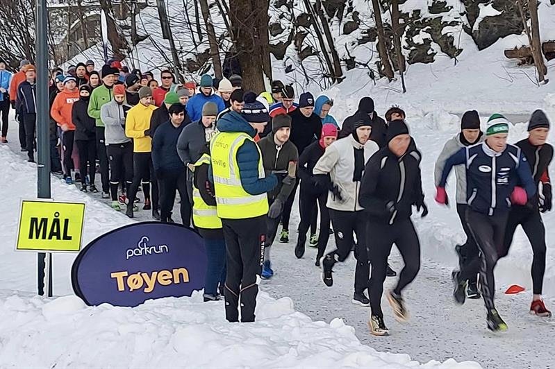 En gruppe mennesker løper på en snødekt vei i Tøyenparken
