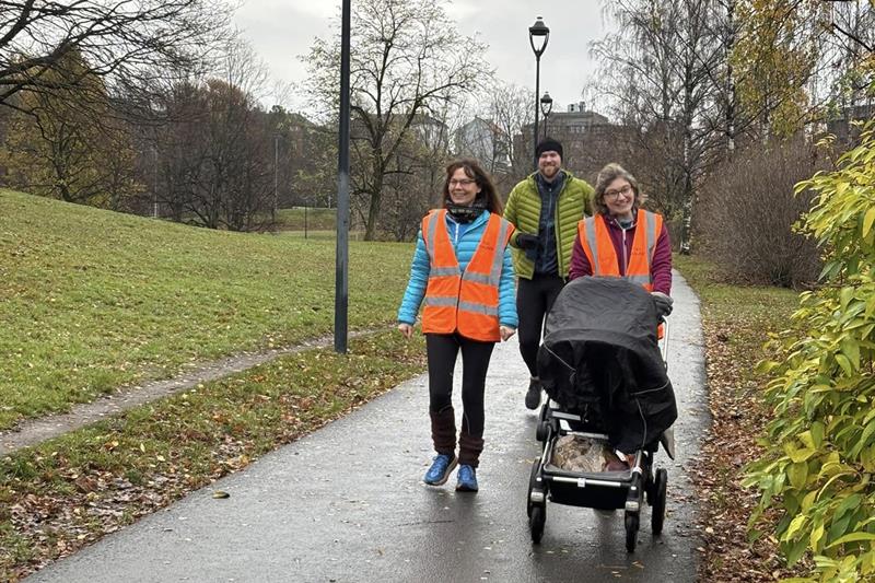 Tre personer på tur i Tøyenparken med barnevogn