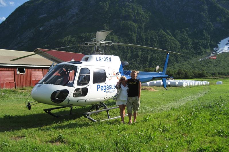 par som poserer foran kameraet foran et helikopter