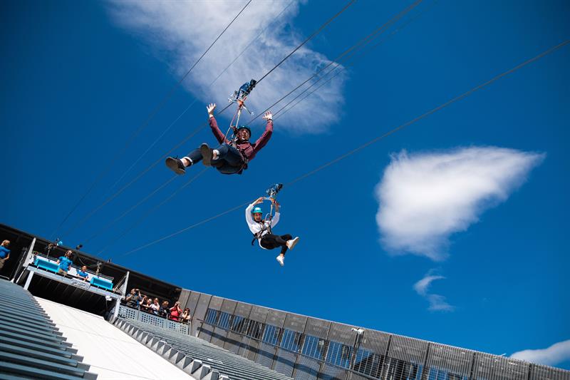 To personer som kjører zipline ned Holmenkollen-hoppbakken.