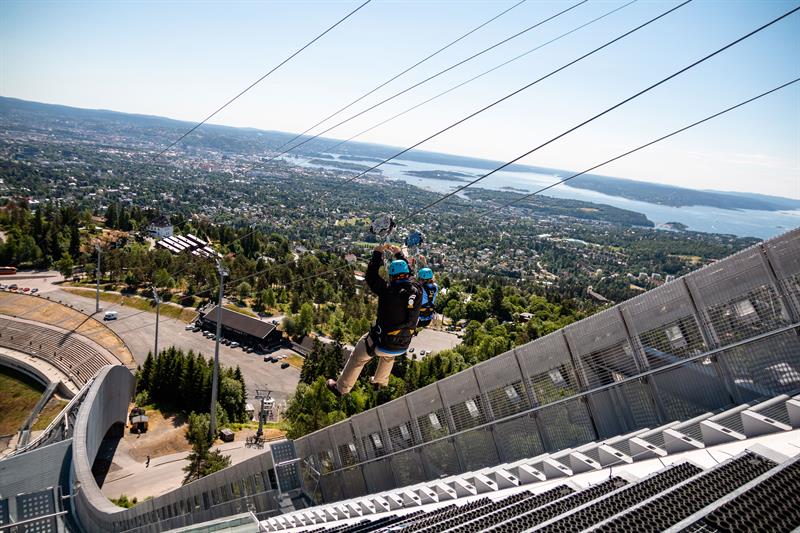 To personer som kjører zipline ned Holmenkollen-hoppbakken.