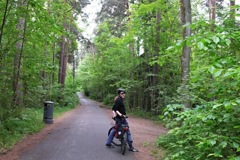 En syklist som står og ser bakover. Skogkledde omgivelser.