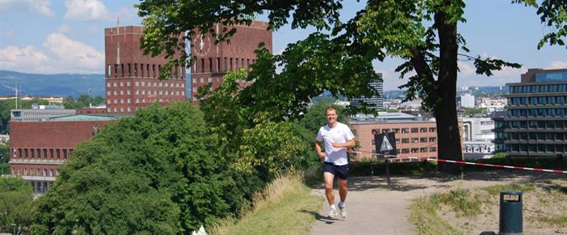 en jogger som løper på en sti med utsikt over Oslo rådhus