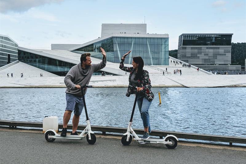 To personer med elscootere foran Operahuset