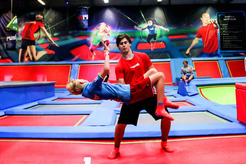 en mann som hjelper en gutt med å gjøre en baklengs salto på en trampoline 