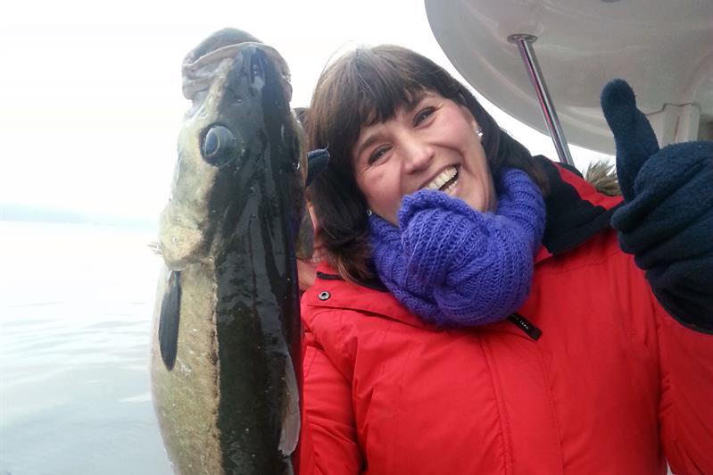 en kvinne i en båt med en fisk i hånden 